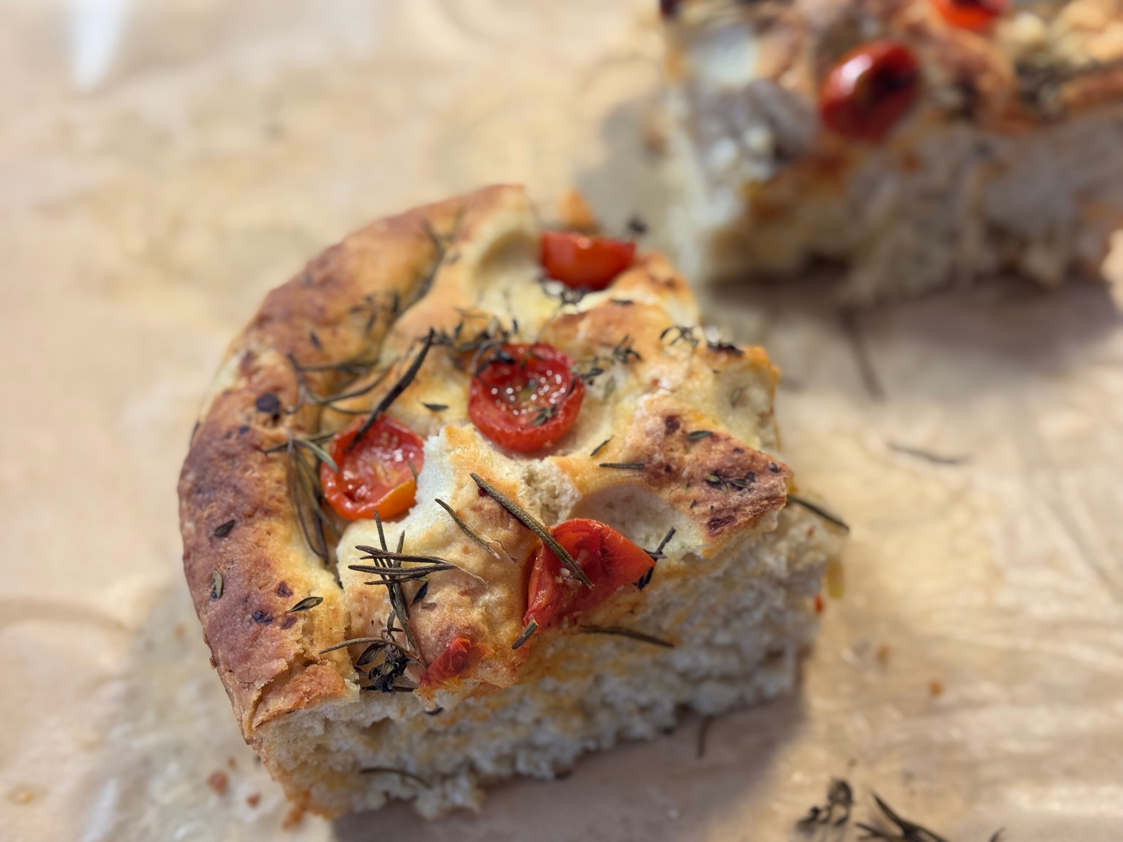 „Ofenfrisches Focaccia-Stück mit Rosmarin und Kirschtomaten – luftiger Brotsnack“