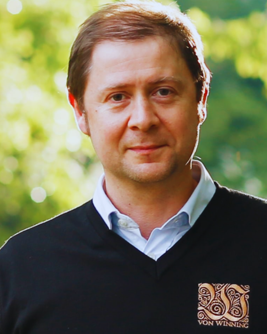 Mann im Freien mit schwarzem Pullover und „Von Winning“-Logo, blickt freundlich in die Kamera.