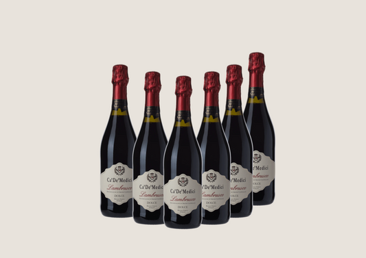Sechs Flaschen Ca’ De’ Medici Lambrusco Dolce mit roter Folie, nebeneinander vor hellem Hintergrund.