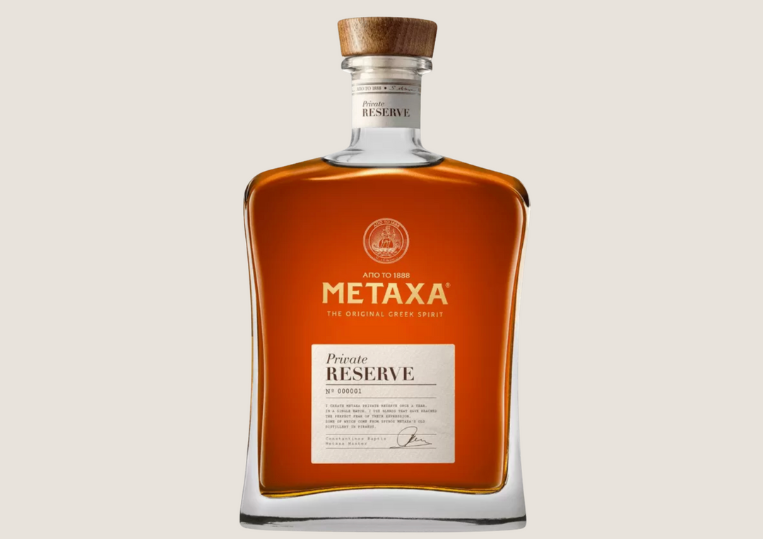 Quadratische Flasche mit braunem Metaxa Private Reserve und Holzverschluss vor hellem Hintergrund.