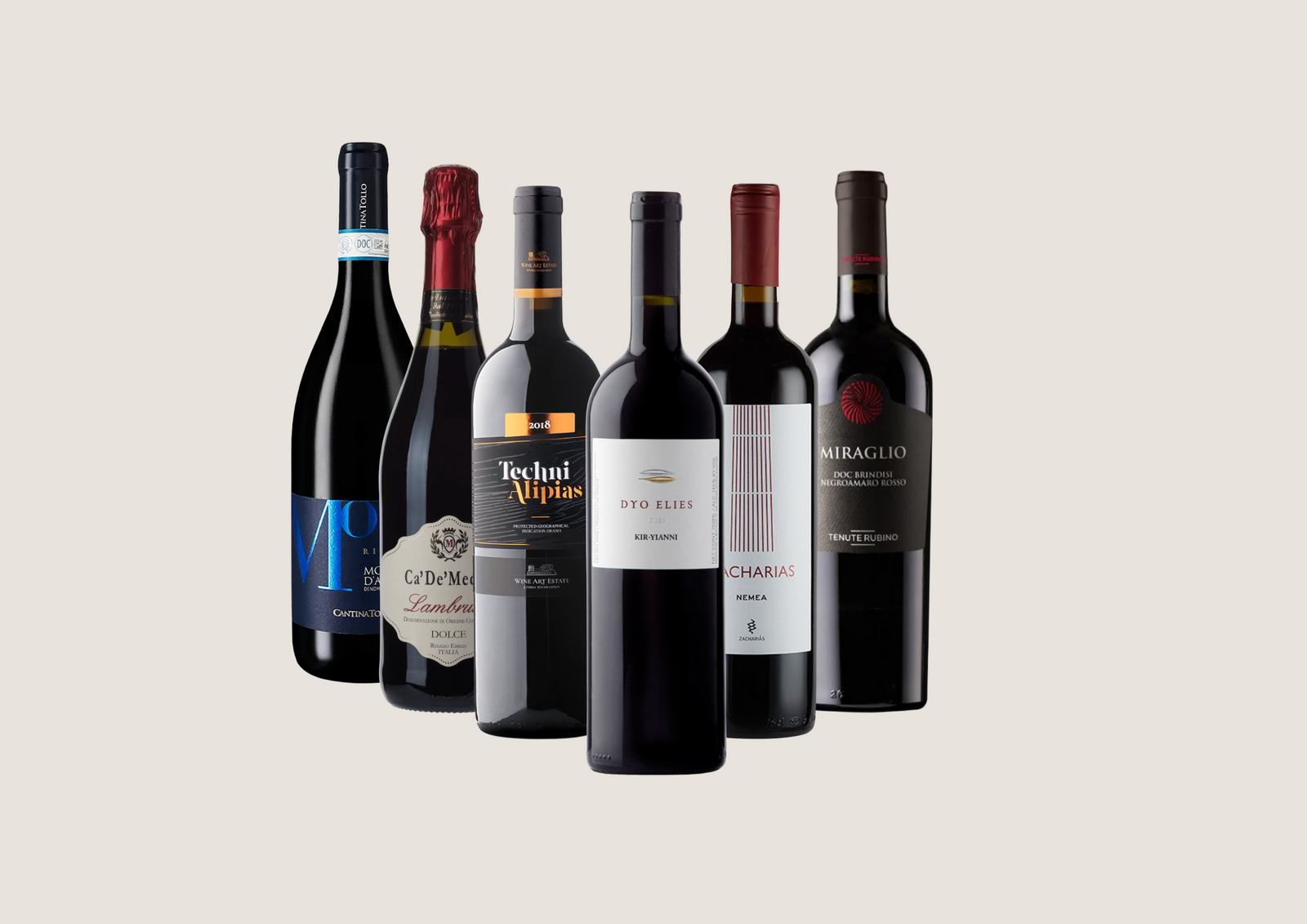 Rotweine aus Italien und Griechenland in eleganten Flaschen nebeneinander auf hellem Hintergrund.