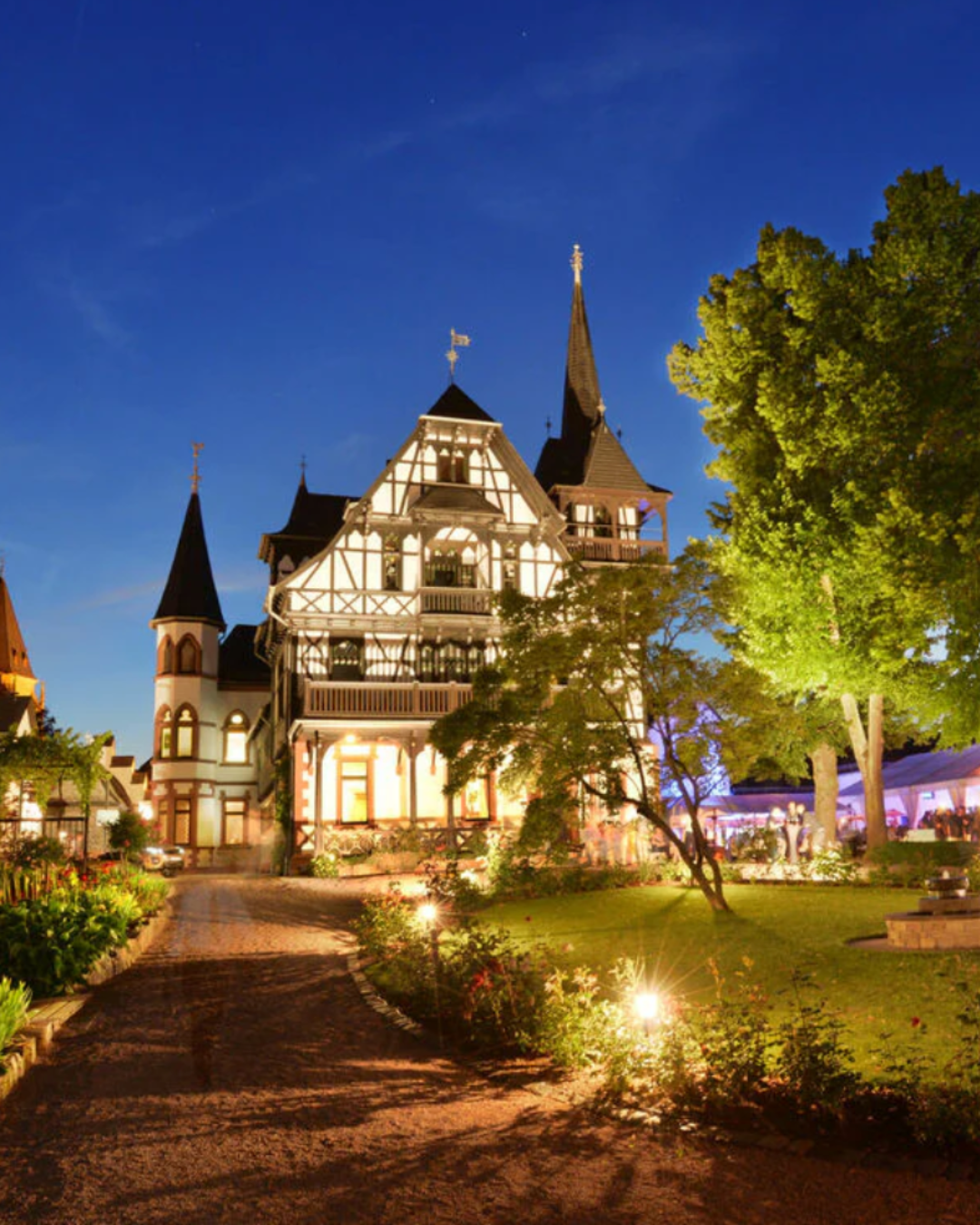 Historisches Weingut bei Sonnenuntergang mit Gartenweg und Beleuchtung.